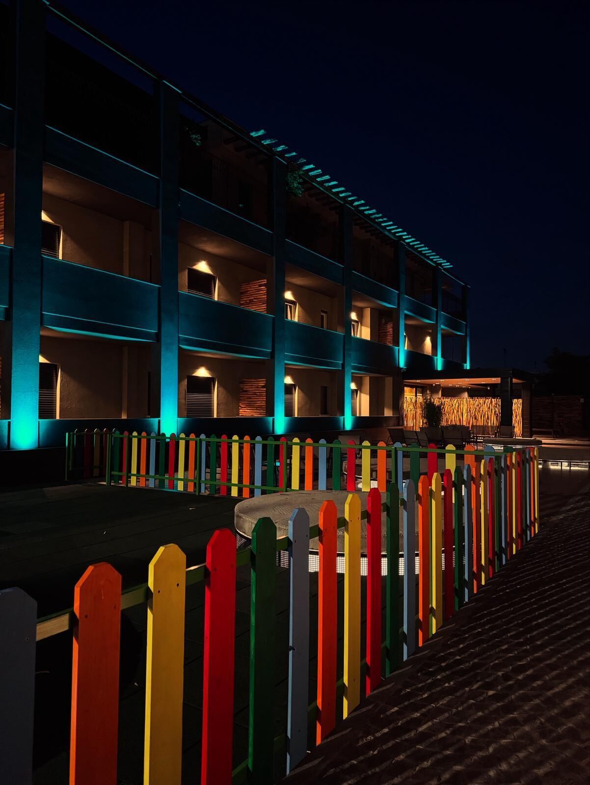 A multi-story hotel with balconies and a colorful fence.