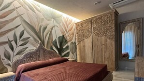 A bedroom with a large bed, a nightstand, a decorative wall, and a wardrobe. - Paradisea club and residences (Volla)