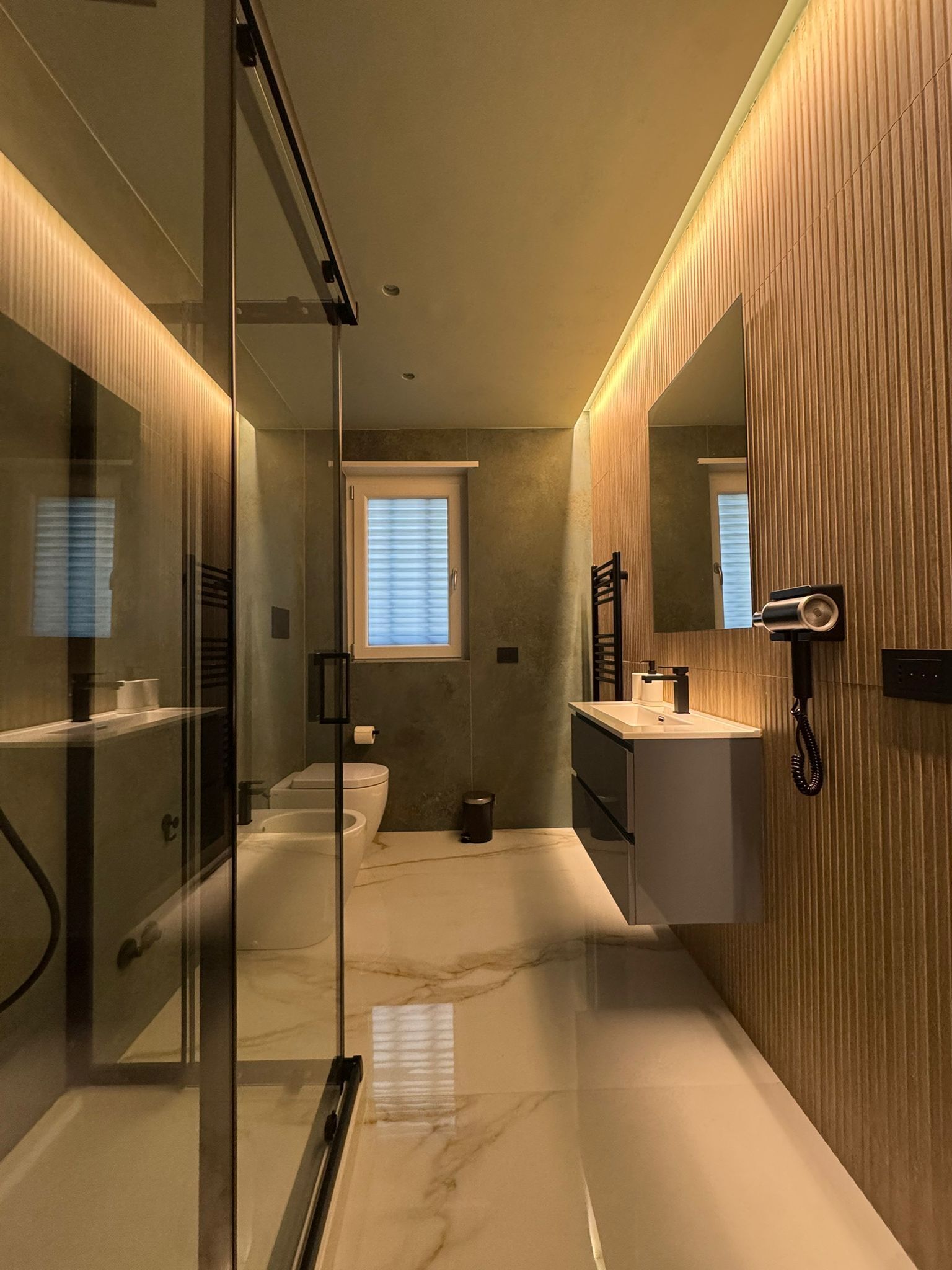 Un baño moderno con cabina de ducha de vidrio, inodoro, lavabo y espejo.