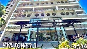 Un edifici de diverses plantes amb disseny modern, que destaca per una entrada de vidre i una sèrie de balcons.