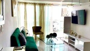 Un saló modern amb un sofà verd, una taula de centre de vidre i un televisor de pantalla plana muntat a la paret.