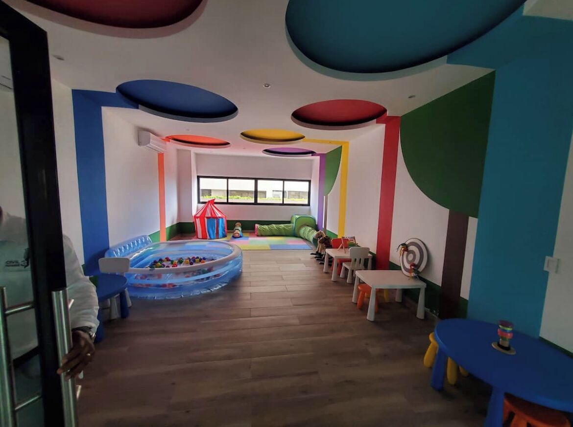 Une pièce aux couleurs vives, avec un espace de jeux comprenant une petite piscine gonflable et des jouets.