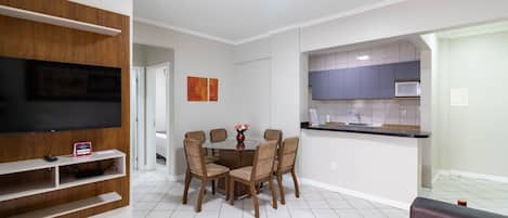 Una sala de estar moderna con una mesa de comedor, sillas, un televisor de pantalla plana y un sofá.