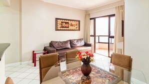 A modern living room with a glass coffee table, a brown sofa, and a framed artwork on the wall. - Fully Equipped Apartments in Meia Praia, 150m From the sea - Eoos (Itapema)