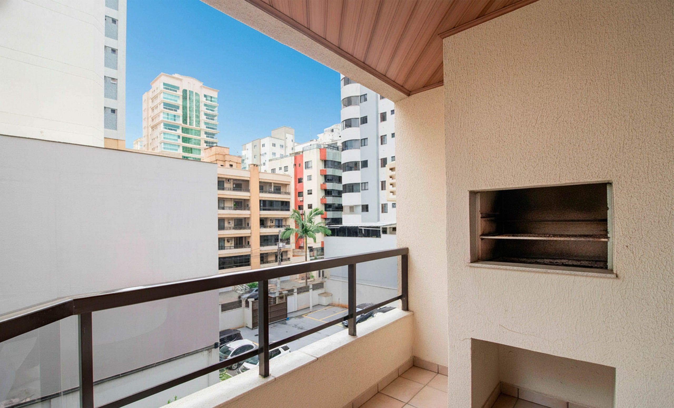Ein Balkon mit Blick auf benachbarte Gebäude, einem kleinen Regal und einem gefliesten Boden.