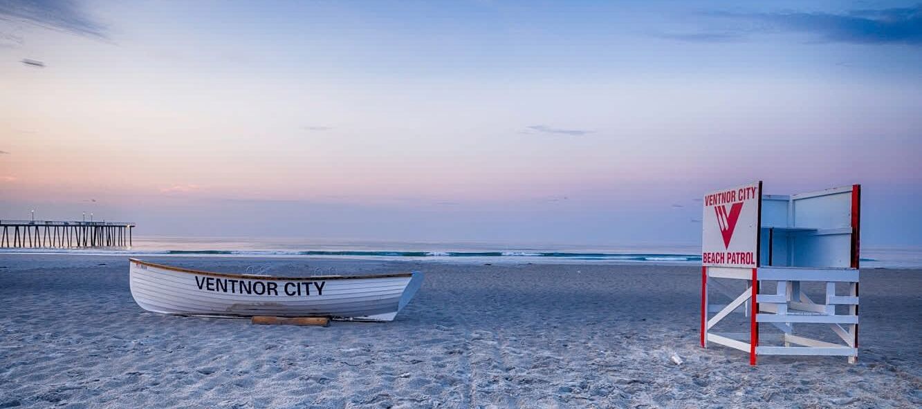 A beach with a lifeguard tower and a boat labeled "VENTNOR CITY" on the sand.