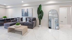 En moderne stue med en grå sofa, et sofabord og et stort spejl.