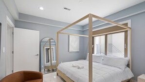 Une chambre à coucher moderne avec un lit à baldaquin, un grand miroir et une vue sur l’extérieur.
