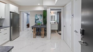 A modern kitchen with white cabinets, a stainless steel refrigerator, and a marble floor. - Ammos Luxury Living- Naxos Suite (Ventnor City)
