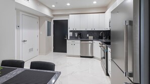 A modern kitchen with white cabinets, stainless steel appliances, and a marble countertop. - Ammos Luxury Living- Naxos Suite (Ventnor City)