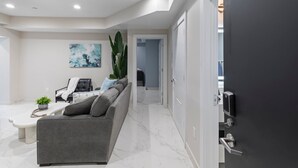Un salon moderne avec un canapé gris, une table basse et une grande plante.