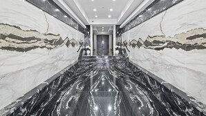A modern hallway with marble walls and floors, leading to a door at the end. - Ammos Luxury Living- Crete Suite (Ventnor City)