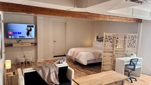 Een moderne kamer met een bed, bureau, bank en een aan de muur bevestigde televisie.