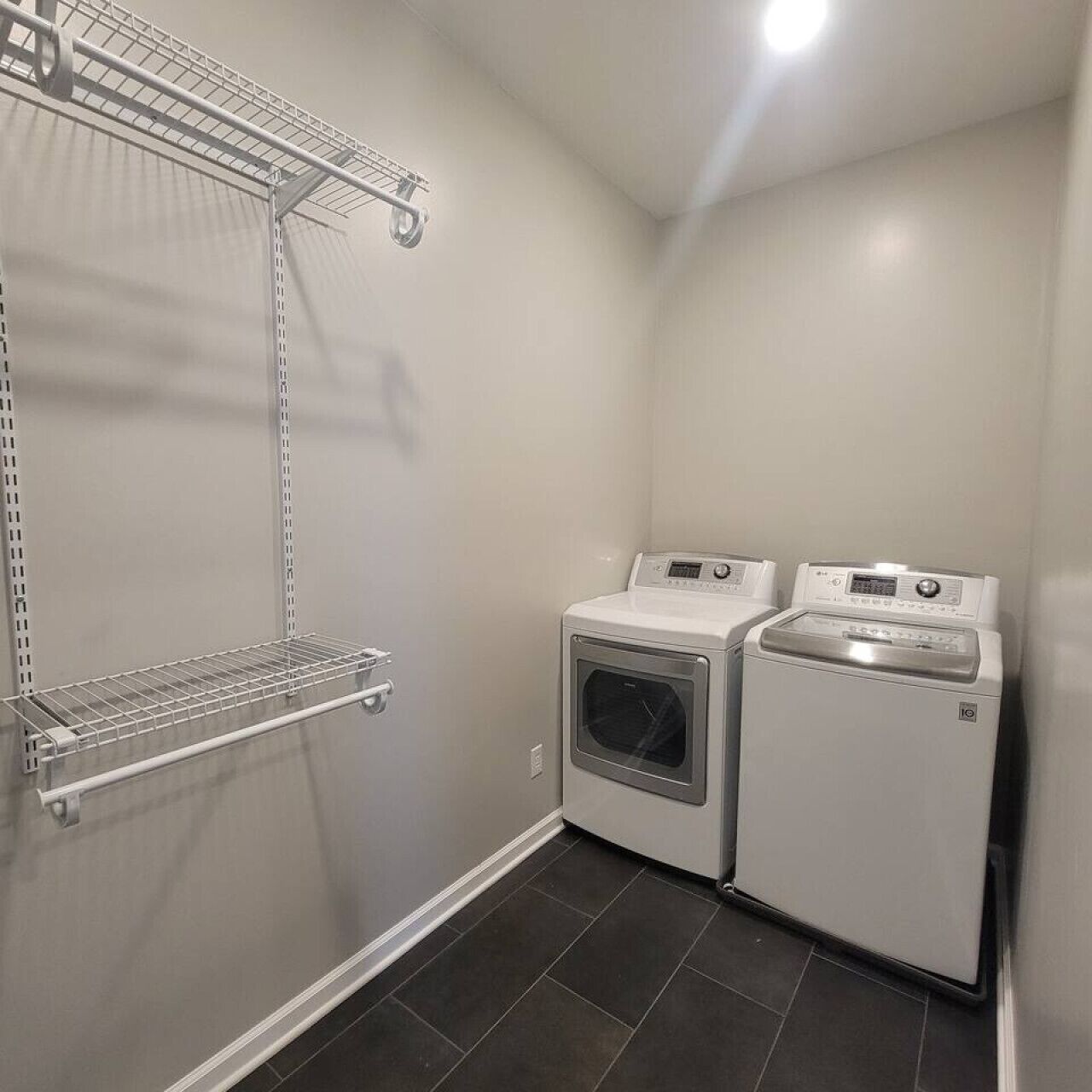 A laundry room with two washing machines and a drying rack.