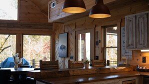 L’intérieur d’un chalet rustique, avec des murs en bois, un comptoir de bar en bois et des luminaires suspendus.