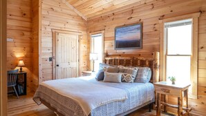 Une chambre dans une cabane en bois, avec un lit, une table de chevet, une chaise et un bureau.