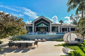 Ein modernes Resort mit großem Pool, Sitzgelegenheiten im Freien und einer tropischen Umgebung.