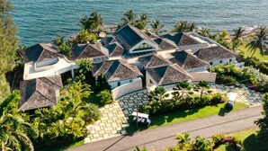 A coastal property with multiple houses, a paved driveway, and a view of the sea. - Oceans 8 Villa 6BR (Sandy Bay)