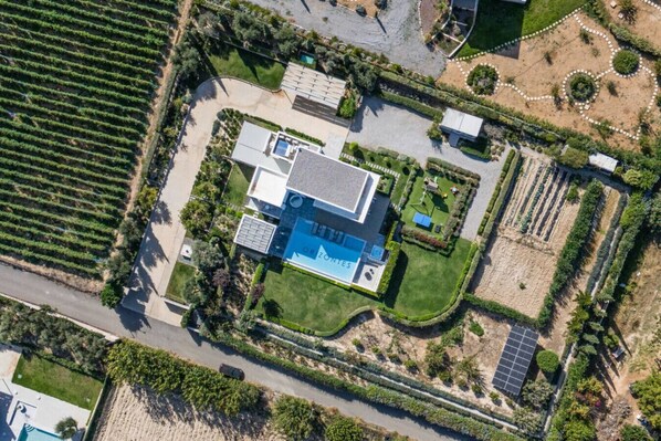 Eine Vogelperspektive zeigt ein Anwesen mit Schwimmbad, Solaranlage und einem gepflegten Garten.