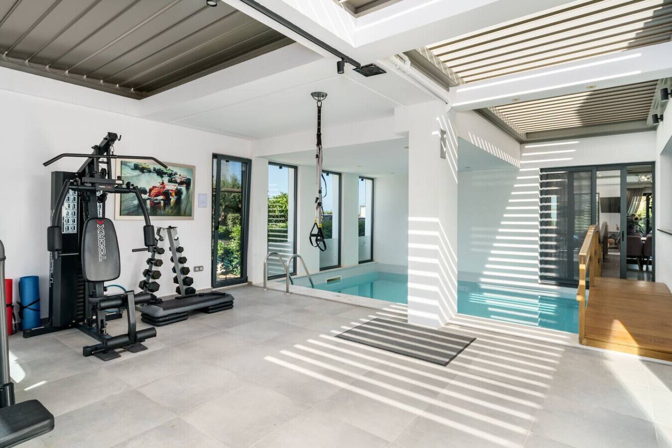 A modern home gym with exercise equipment, a pool, and a dining area.