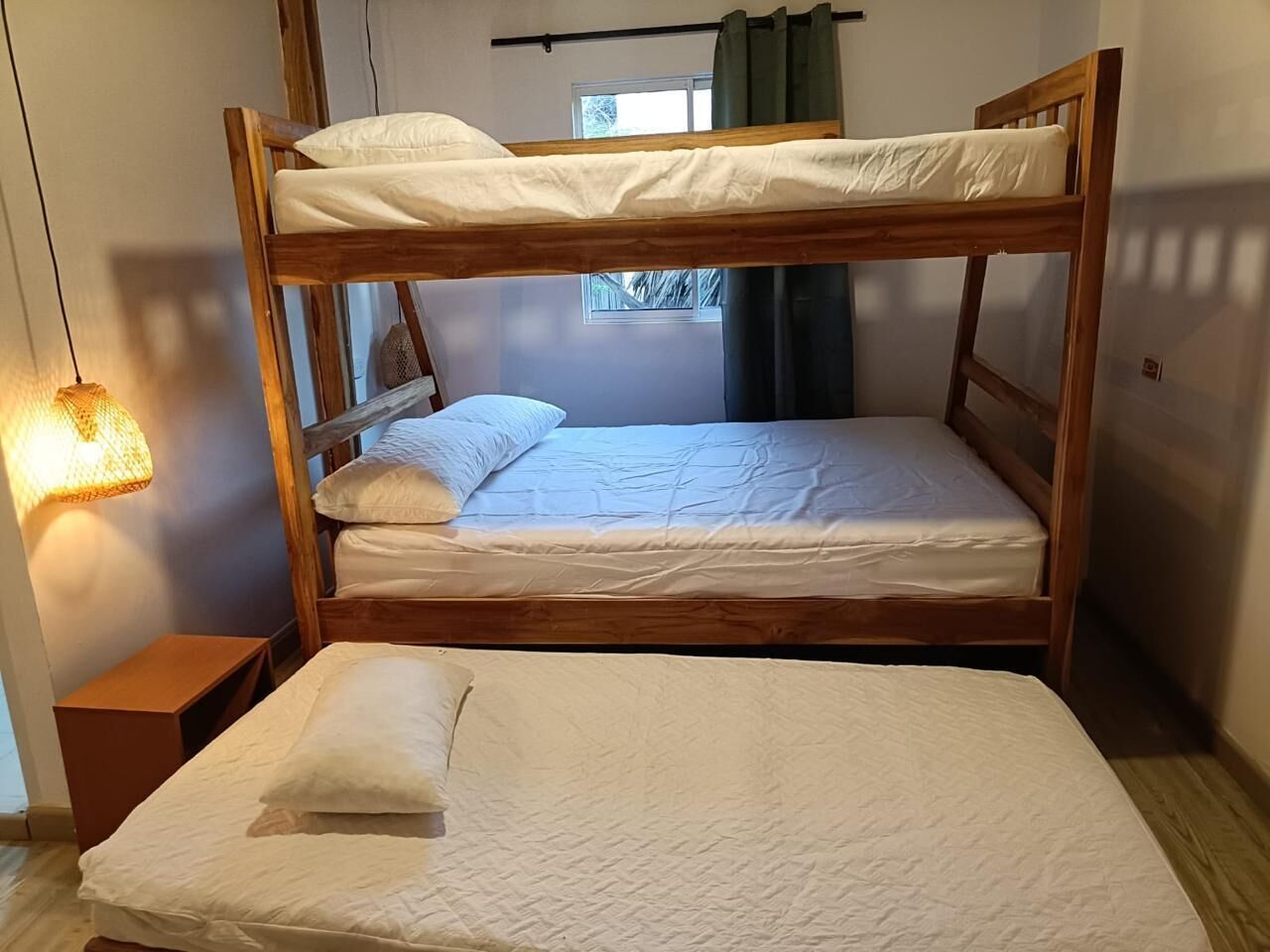 A bunk bed with two levels, a bedside table, and a lamp.