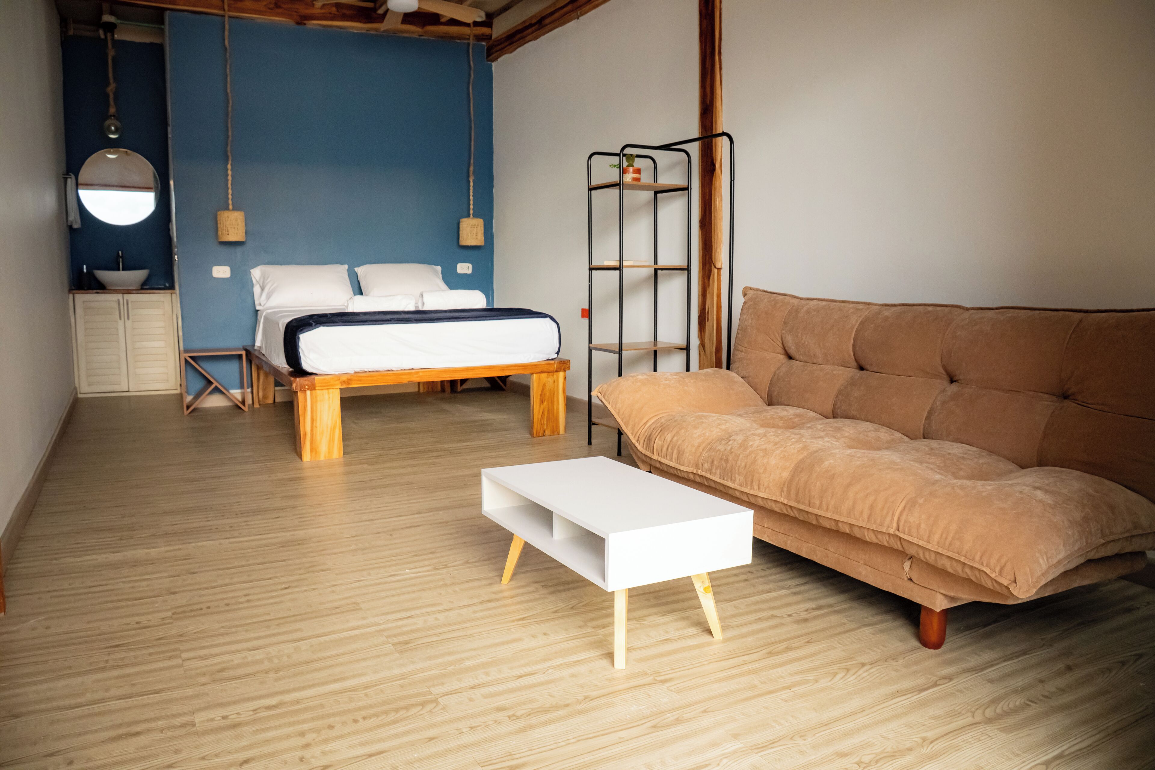 A bedroom with a bed, a sofa, a bedside table, a wardrobe, and a hanging light fixture.