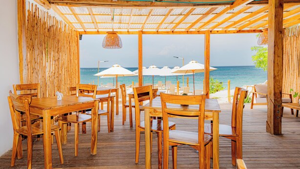 An outdoor wooden deck with tables and chairs, overlooking the sea. - Mar Barú Beach House (Cartagena)