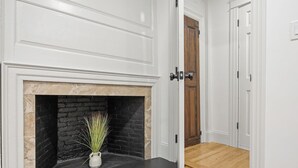 Une pièce avec une cheminée, une porte en bois et un mur blanc.