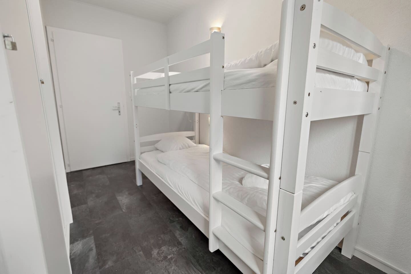 Et soveværelse med køjeseng, dør og lysarmatur.