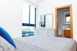 Un dormitorio con una cama grande, un aparador, un espejo y vistas a un balcón.