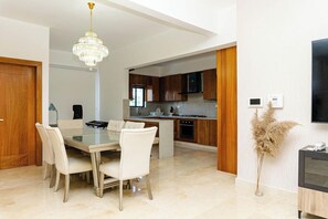 Uma cozinha moderna com armários de madeira, uma ilha central e uma área de jantar com mesa e cadeiras de vidro.