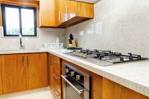 Una cocina con armarios de madera, una estufa de acero inoxidable y un ventanal.