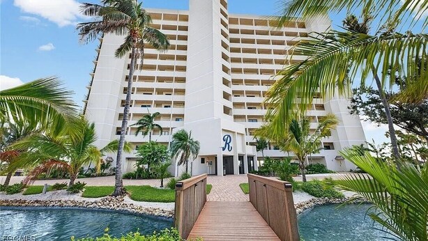 A hotel with a central tower, a pool, and a wooden bridge.