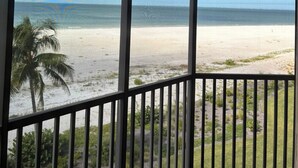 A room with a large window overlooking a beach and ocean.