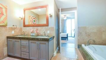 Une salle de bain moderne avec un lavabo surmonté d’un plan de travail en granit, un grand miroir et une baignoire séparée.