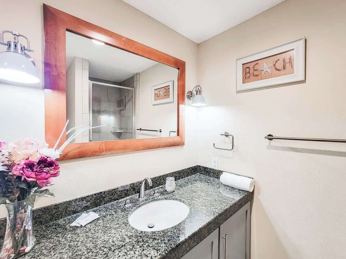 A bathroom with a granite countertop sink, a large mirror, and a towel rack.