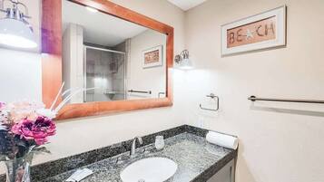 A bathroom with a granite countertop sink, a large mirror, and a towel rack.