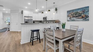 A modern kitchen with white cabinetry, a stainless steel refrigerator, and pendant lighting. - Luxury Pondside Retreat (Murrells Inlet)