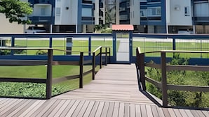 A modern urban residential area with high-rise buildings, a wooden deck, and a green space. - Apartamento Itapema (Itapema)