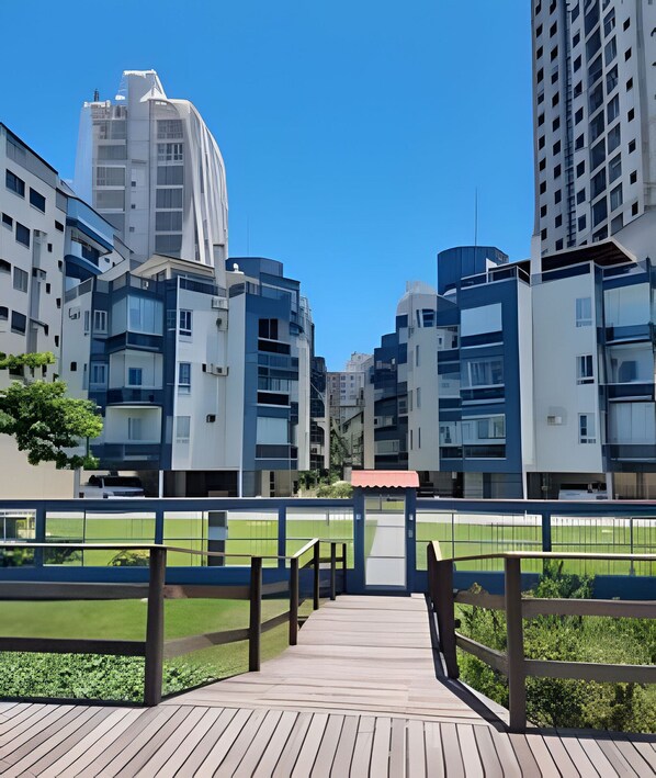 A modern urban residential area with high-rise buildings, a wooden deck, and a green space.