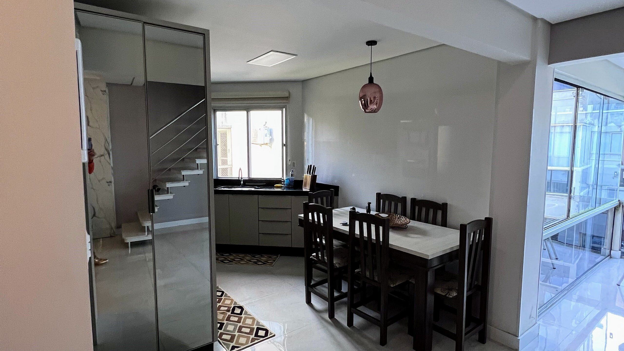 A compact kitchen with a dining area, a staircase, and a view through a glass door.