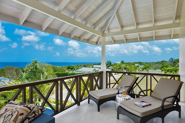 Balcony with lounge chairs, ocean views, tropical greenery, and vaulted ceiling