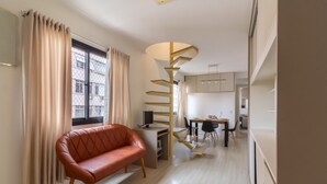 Una sala de estar moderna con sofá, una escalera en espiral, un comedor y una cocina.