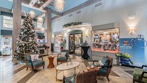 A spacious lobby with a large Christmas tree, comfortable seating, and a Toy Story Band store.