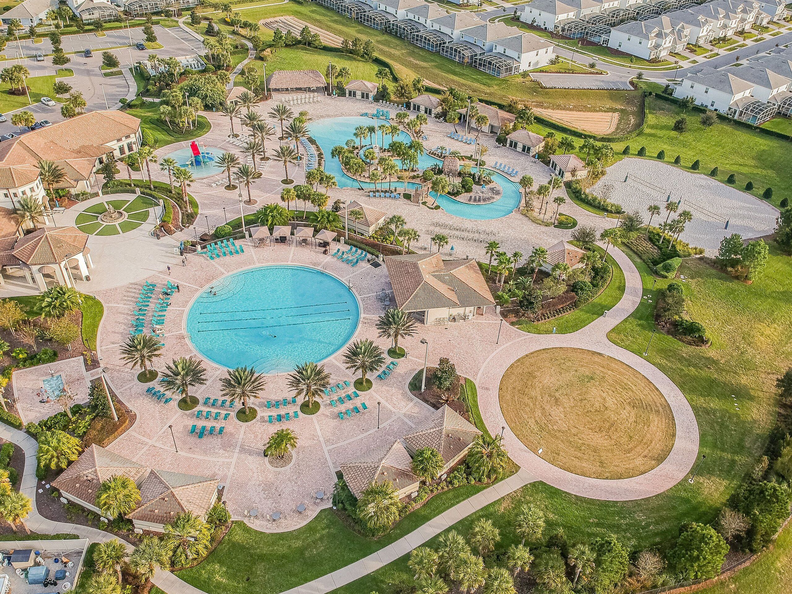 An aerial view of a resort with multiple swimming pools, sun loungers, and palm trees.