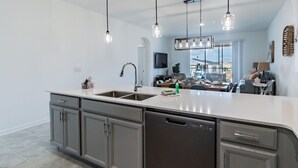 A modern kitchen with a large island, stainless steel appliances, and pendant lighting.