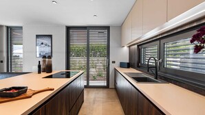 A modern kitchen with a central island, dark wood cabinets, and a large window with blinds. - Villa Visignano with heated pool and welness facilities (Višnjan)