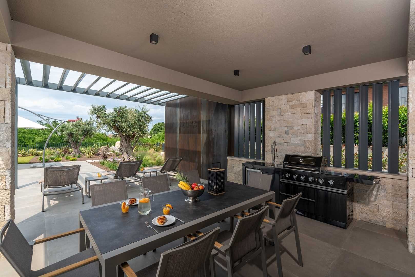 An outdoor dining area with a table, chairs, and a grill.