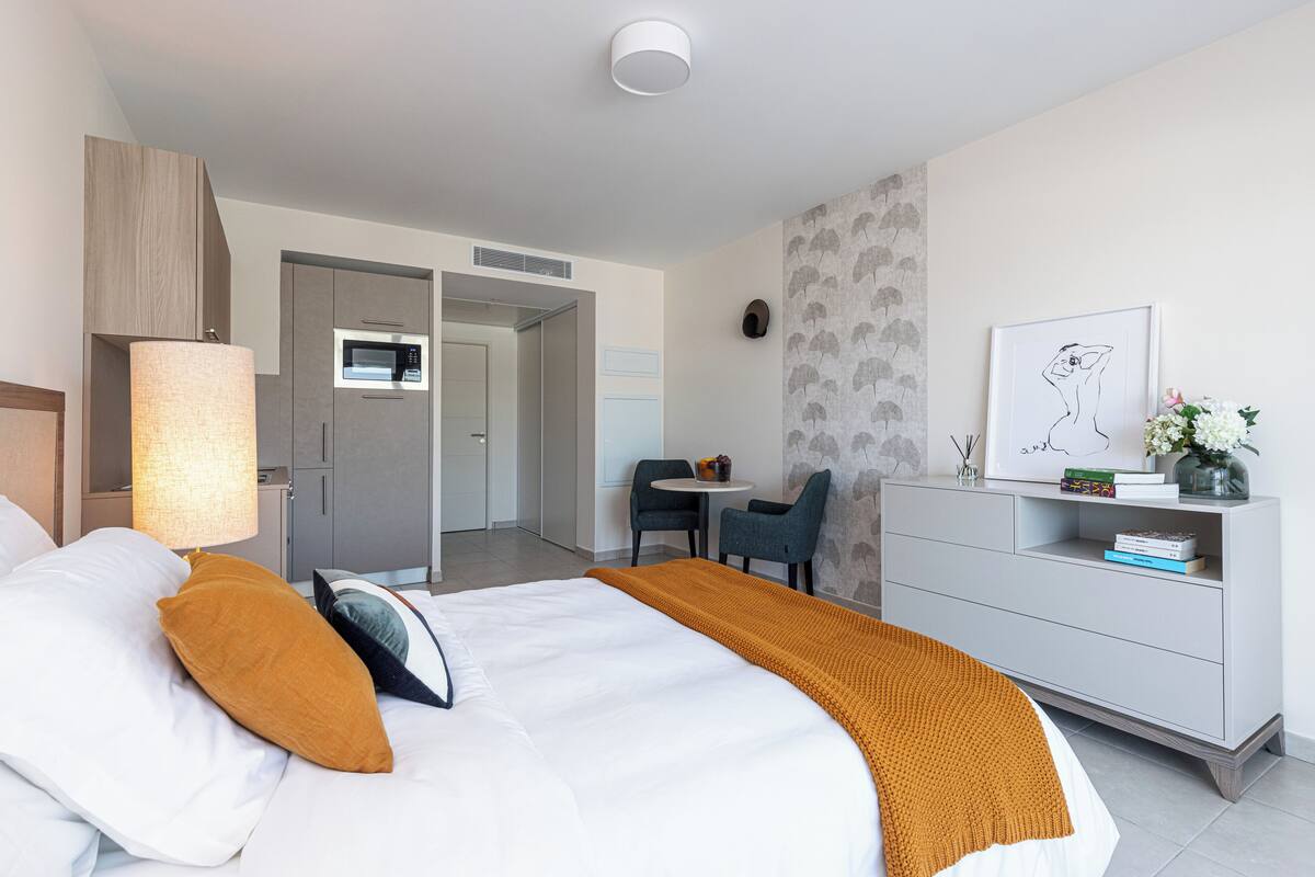 A modern hotel room with a large bed, a desk, and a seating area.