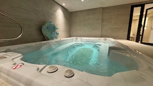 Een moderne, overdekte hottub met een helder wateroppervlak, omringd door wanden in neutrale tinten en een eigentijds design.